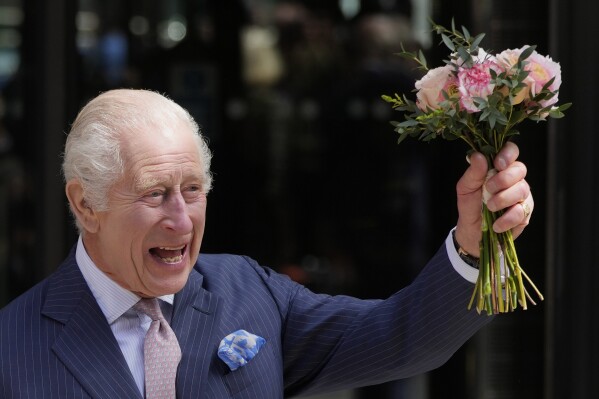 Britain's King Charles III holds up flowers he was given as he leaves after a visit to University College Hospital Macmillan Cancer Centre in London, Tuesday, April 30, 2024. (AP Photo/Kin Cheung, File)