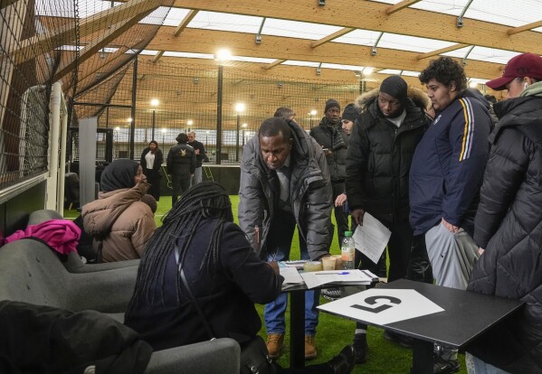 Job seekers line up to get the application papers during the Olympics jobs fair at sport center in Paris, Thursday, Dec. 14, 2023. (AP Photo/Michel Euler)