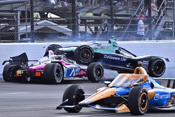 Marcus Ericsson (28), of Sweden, goes over the top of Tom Blomqvist, of England, as the collide in the first turn during the Indianapolis 500 auto race at Indianapolis Motor Speedway in Indianapolis, Sunday, May 26, 2024. (AP Photo/Marty Seppala)