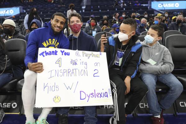 FILE - Golden State Warriors guard Gary Payton II, left, greets young fans from the group Decoding Dyslexia California, before the team's NBA basketball game against the Detroit Pistons in San Francisco, Tuesday, Jan. 18, 2022. Warriors guard Gary Payton II faced daunting challenges reading as a boy because of dyslexia that was diagnosed in second grade. He's now an NBA star with Golden State and he's finding ways to support Bay Area youth with similar learning disabilities to give them tools and courage to push forward when everything feels hard. (AP Photo/Jed Jacobsohn, File)