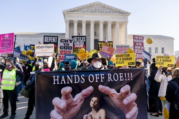 FILE -Stephen Parlato of Boulder, Colo., holds a sign that reads "Hands Off Roe!!!" as abortion rights advocates and anti-abortion protesters demonstrate in front of the U.S. Supreme Court, Wednesday, Dec. 1, 2021, in Washington. A recent Alabama Supreme Court ruling that frozen embryos are legally protected children is highlighting how support for fetal personhood underpins far less dramatic laws and proposals from abortion foes in states across the U.S. (AP Photo/Andrew Harnik, File)