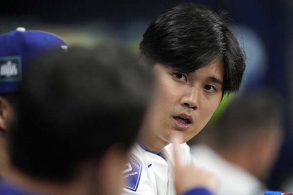Los Angeles Dodgers designated hitter Shohei Ohtani, right, talks with interpreter Will Ireton during the fourth inning of a baseball game against the San Diego Padres at the Gocheok Sky Dome in Seoul, South Korea Thursday, March 21, 2024, in Seoul, South Korea. (AP Photo/Lee Jin-man)
