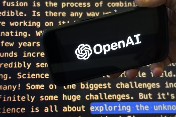File - The OpenAI logo appears on a mobile phone in front of a screen showing part of the company website in this photo taken on Nov. 21, 2023 in New York. Negotiators will meet this week to hammer out details of European Union artificial intelligence rules but the process has been bogged down by a simmering last-minute battle over how to govern systems that underpin general purpose AI services like OpenAI's ChatGPT and Google's Bard chatbot. (APPhoto/Peter Morgan, File)