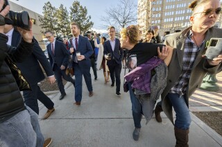 Chrystina Page, right, holds back Heather De Wolf, as she yells at Jon Hallford, left, the owner of Back to Nature Funeral Home, as he leaves with his lawyers following a preliminary hearing, Thursday, Feb. 8, 2024, outside the El Paso County Judicial Building in Colorado Springs, Colo. Hallford and his wife, Carie Hallford, are each charged with 190 counts of abuse of a corpse, five counts of theft, four counts of money laundering and over 50 counts of forgery. De Wolf and Page are mothers of sons believed to be among the bodies found at the funeral home. (Christian Murdock/The Gazette via AP)