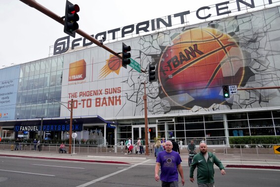 FILE - Fans walks past the Footprint Center, Tuesday, March 14, 2023, in Phoenix. New Phoenix Suns owner Mat Ishbia wasted little time overhauling his team's roster. Now, he's turned his attention to the fan experience at Footprint Center. (AP Photo/Matt York)