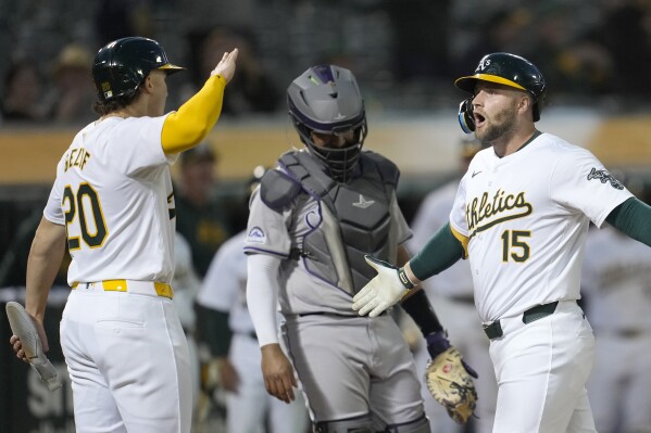 Oakland Athletics' Seth Brown (15) celebrates after hitting a two-run home run that also scored Zack Gelof (20) as Colorado Rockies catcher Elias Díaz, middle, reacts during the seventh inning of a baseball game in Oakland, Calif., Tuesday, May 21, 2024. (AP Photo/Jeff Chiu)