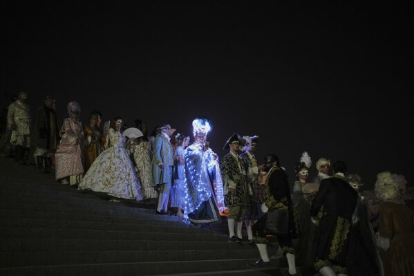 Costumed guests arrive for the Great Masked Ball in the Orangerie of the Versailles castle, outside Paris, Saturday, June 21, 2025. (AP Photo/Christophe Ena)