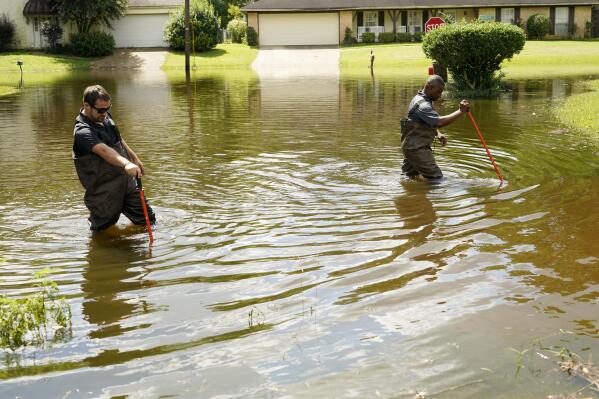 Hinds County Emergency Management Operations deputy director Tracy Funches, right, and operations coordinator Luke Chennault, wade through flood waters in northeast Jackson, Miss., Monday, Aug. 29, 2022, as they check water levels. Flooding affected a number neighborhoods that are near the Pearl River. (AP Photo/Rogelio V. Solis)