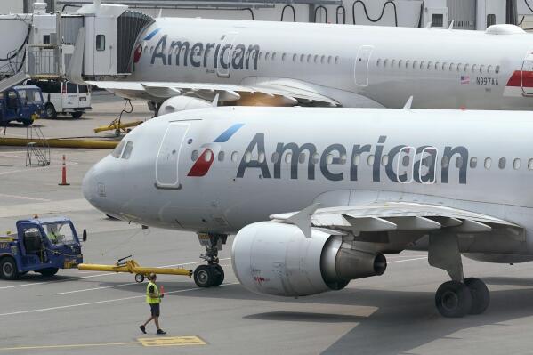 FILE - American Airlines passenger jets prepare for departure on July 21, 2021, near a terminal at Boston Logan International Airport, in Boston. The airliner is raising its forecast of third-quarter revenue based on a strong summer for travel. American said Tuesday, Oct. 11, 2022, that revenue rose about 13% over the same quarter in 2019, before the pandemic, but that costs also increased sharply. (AP Photo/Steven Senne, File)