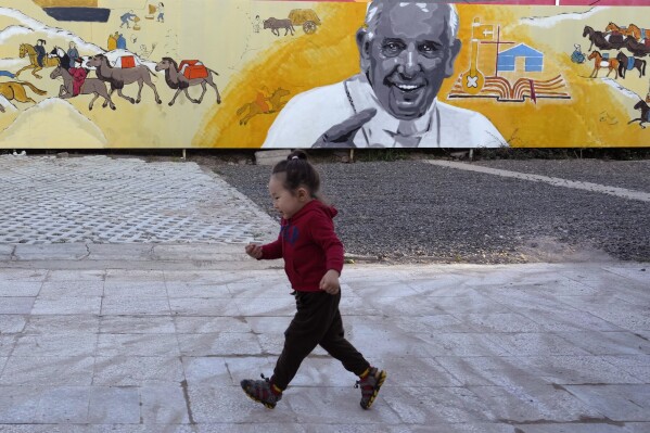 A child runs past a mural showing Pope Francis with depiction of nomadic daily life in Mongolian outside a church in Ulaanbaatar, Monday, Aug. 28, 2023. When Pope Francis travels to Mongolia this week, he will in some ways be completing a mission begun by the 13th century Pope Innocent IV, who dispatched emissaries east to ascertain the intentions of the rapidly expanding Mongol Empire and beseech its leaders to halt the bloodshed and convert.(AP Photo/Ng Han Guan)
