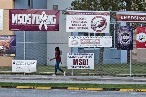 FILE - A student arrives for school at Marjory Stoneman Douglas High School during the one-year anniversary of the school shooting, Thursday, Feb. 14, 2019, in Parkland, Fla. The 2018 Parkland high school massacre will be reenacted with the firing of about 140 blanks on campus as part of families' lawsuits against the former sheriff's deputy they accuse of failing to stop the gunman, a judge ruled Wednesday, July 12, 2023. (Al Diaz/Miami Herald via AP)