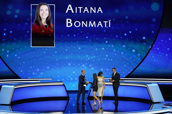 Spain's Aitana Bonmati, second from left, receives the UEFA Women's Player of the Year for 2022/23 award from UEFA President Aleksander Ceferin, right, after the 2023/24 UEFA Champions League group stage draw at the Grimaldi Forum in Monaco, Thursday, Aug. 31, 2013. (AP Photo/Daniel Cole)