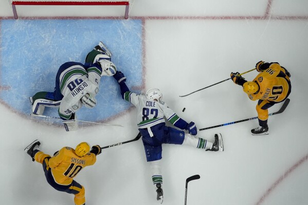 Vancouver Canucks defenseman Ian Cole (82) and goaltender Casey DeSmith (29) defend the goal against Nashville Predators center Ryan O'Reilly (90) and center Colton Sissons (10) during the third period in Game 3 of an NHL hockey Stanley Cup first-round playoff series Friday, April 26, 2024, in Nashville, Tenn. The Canucks won 2-1. (AP Photo/George Walker IV)