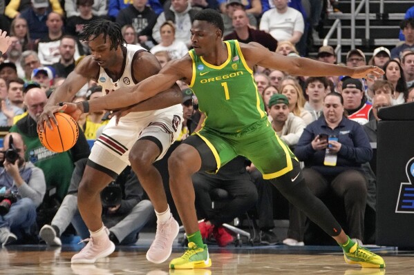 Oregon's N'Faly Dante (1) knocks the ball away from South Carolina's Josh Gray, left, during the first half of a first-round college basketball game in the NCAA Tournament in Pittsburgh, Thursday, March 21, 2024. (AP Photo/Gene J. Puskar)