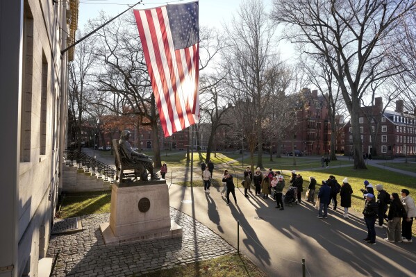 FILE - People take photos near a John Harvard statue, left, on the Harvard University campus, Jan. 2, 2024, in Cambridge, Mass. In a letter Monday, Feb. 19, to the school community, Harvard University condemned what it called a 鈥渇lagrantly antisemitic cartoon鈥� posted on social media over the weekend by a group that includes students and faculty. (AP Photo/Steven Senne, File)