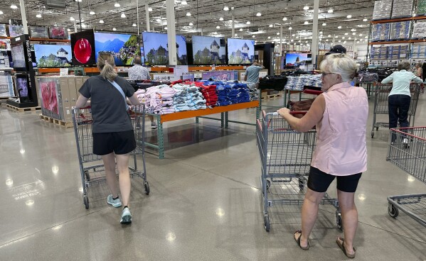 File - Shoppers push carts into a Costco warehouse Friday, Aug. 4, 2023, in Thornton, Colo. A surge in U.S. consumer spending is fueling economic growth, reflecting a resilience among households that has confounded economists, Federal Reserve officials and even the sentiments that Americans themselves have expressed in surveys.(AP Photo/David Zalubowski, File)