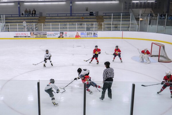 CORRECTS SPELLING FROM ORNO TO ORONO - Players on the Minneapolis, white and black uniforms, and Orono, red uniforms, teams compete in a 10-and-under youth hockey game Feb. 4, 2024, in Minneapolis. (AP Photo/Abbie Parr)