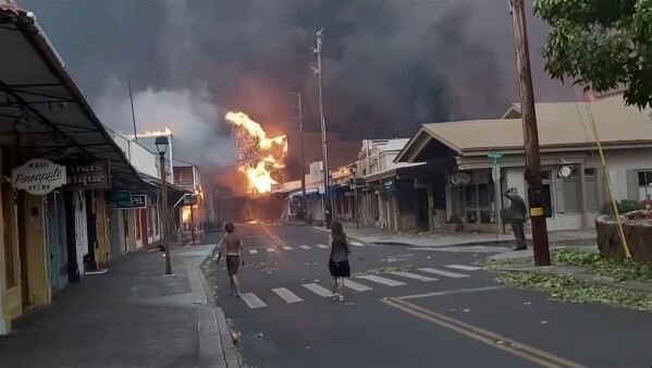 People watch as smoke and flames fill the air from raging wildfires on Front Street in downtown Lahaina, Maui.