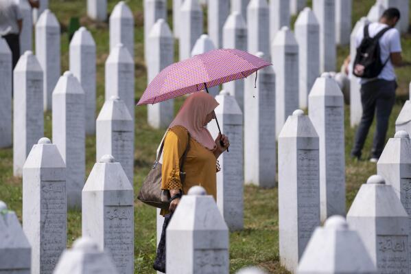A woman visits the memorial cemetery in Potocari near Srebrenica, Bosnia, Sunday, July 11, 2021. Bosnia is marking the 26th anniversary of the Srebrenica massacre, the only episode of its 1992-95 fratricidal war that has been declared a genocide by international and national courts. The brutal execution of more than 8,000 Muslim Bosniaks by Bosnian Serb troops is being commemorated by a series of events Sunday. (AP Photo/Darko Bandic)