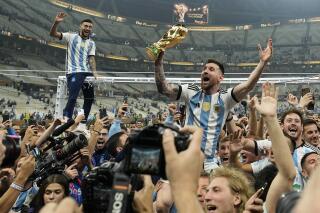 Argentina's Lionel Messi celebrates with the trophy in front of fans after winning the World Cup final soccer match between Argentina and France at the Lusail Stadium in Lusail, Qatar, Dec. 18, 2022. Argentina won 4-2 in a penalty shootout after the match ended tied 3-3. (AP Photo/Martin Meissner)