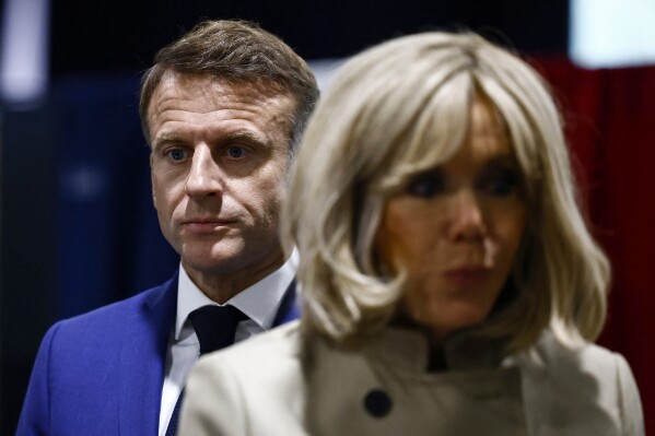 French President Emmanuel Macron and his wife Brigitte Macron stand in the voting station before voting in Le Touquet-Paris-Plage, northern France, Sunday, June 30, 2024. (Yara Nardi, Pool via AP)