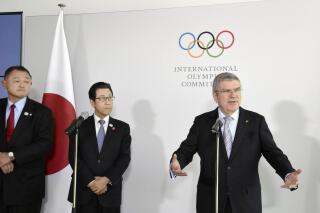 Japanese Olympic Committee President Yasuhiro Yamashita, from left, and Sapporo Mayor Katsuhiro Akimoto listen to International Olympic Committee President Thomas Bach, right, speak during a news conference in Lausanne, Switzerland, on Jan. 11, 2020. Sapporo's bid for the 2030 Winter Olympics has been slowed, but not stopped, by fallout from the still-developing corruption scandal around the 2020 Tokyo Games. (Masashi Inoue/Kyodo News via AP)