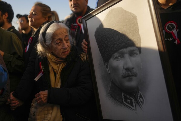 FILE - A woman looks at a portrait of Turkey's founding father Mustafa Kemal Ataturk as she waits with others to pay respect during the 84th anniversary of his death at Dolmabahce palace in Istanbul, Turkey, on Nov. 10, 2022. Turkey's broadcasting watchdog has launched an investigation into claims that digital platform Disney+ pulled a series on the country's founder Mustafa Kemal Ataturk, the group's chairman said. (AP Photo/Francisco Seco, File)