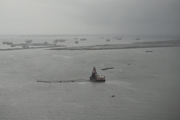 Barges are seen beside reclamation sites in the rain in Manila bay, Philippines on Wednesday, Aug. 2, 2023, The United States expressed concerns over major reclamation projects near its heavily secured embassy, which sits on one edge of Manila Bay, due to the involvement of a blacklisted Chinese company, the U.S. Embassy said Wednesday. (AP Photo/Aaron Favila)