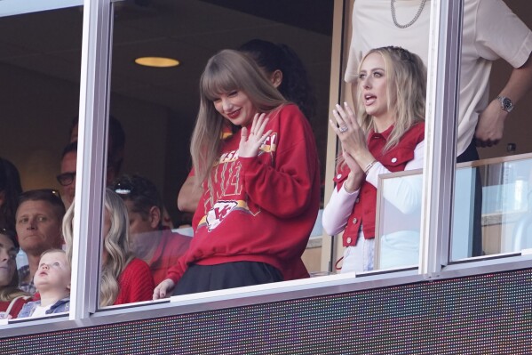 FILE - Taylor Swift waves from a suite alongside Brittany Mahomes, right, during the first half of an NFL football game between the Kansas City Chiefs and the Los Angeles Chargers, Oct. 22, 2023, in Kansas City, Mo. A friendship bracelet with a phone number: that's how Kelce planned to woo Swift when he went to her Eras Tour concert stop in the Missouri capital. The romance that united sports and music fans, a celestial wonder that drew millions of eyes skyward and a long overdue homecoming for some Native American tribes were just some of the moments that inspired us and brought joy in 2023. (AP Photo/Ed Zurga, File)