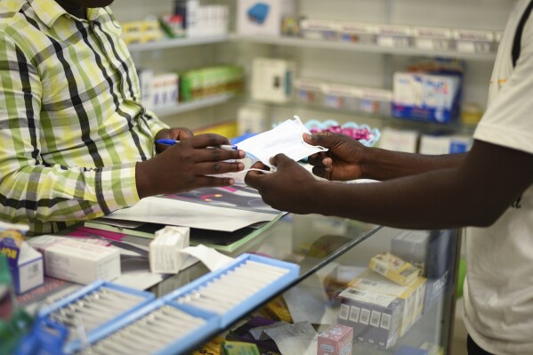 FILE — In this Feb. 6, 2020 file photo, a man buys a face mask at a pharmacy in Kitwe, Zambia. Zambia faces a Friday deadline to clear debt owed to external investors who have rejected the country's request for deferral of an overdue $42.5 million interest payment amid the coronavirus pandemic. (AP Photo/Emmanuel Mwiche/File)