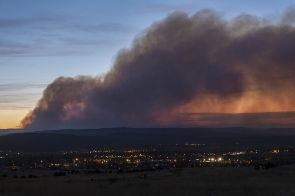 FILE - Smoke from the Calf Canyon/Hermits Peak Fire drifts over Las Vegas, N.M., on May 7, 2022. Federal emergency managers said Friday, Aug. 4, 2023, that they’re making more progress in compensating victims of the Hermits Peak/Calf Canyon wildfires sparked last year by the U.S. Forest Service. (Robert Browman/The Albuquerque Journal via AP, File)