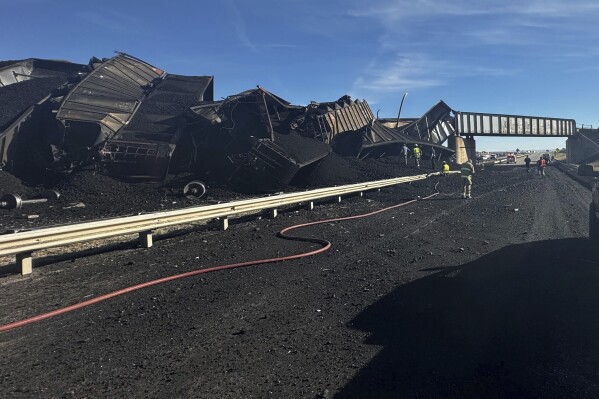 In this photo released by the Pueblo County Sheriff's Office, police respond to the scene of a train derailment near Pueblo, Colo., Sunday, Oct. 15, 2023. The train derailment Sunday spewed coal and mangled train cars across the highway. (Joshua Johnson/Pueblo County Sheriff's Office via AP)