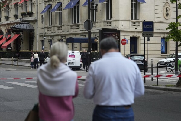 Tourists watch the entrance of the Harry Winston jewelry after a robbery in Paris, Saturday, May 18, 2024. French police investigators were hunting Saturday for armed robbers on motorbikes who hit a jewelry store on one of Paris' poshest streets, and media reports said the target was the exclusive Harry Winston boutique, self-described "Jeweler to the Stars." (AP Photo/Thibault Camus)