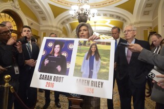 FILE - Sen. Joni Ernst, R-Iowa, holds a poster with photos of murder victims Sarah Root and Laken Riley as she speaks on Capitol Hill, Feb. 27, 2024, in Washington. House Republicans have passed a bill that would require federal authorities to detain unauthorized immigrants who have been accused of theft, seizing on the recent death of Laken, a nursing student in Georgia. The bill sends a rebuke to President Joe Biden’s border policies just hours ahead of his State of the Union address. However, the nine-page bill had little chance of being taken up in the Democratic-controlled Senate. (AP Photo/Mark Schiefelbein, File)