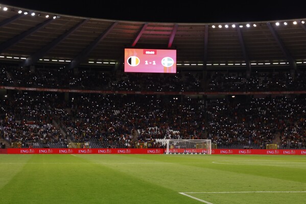 Supporters lit their mobile phones lights after suspension of the Euro 2024 group F qualifying soccer match between Belgium and Sweden at the King Baudouin Stadium in Brussels, Monday, Oct. 16, 2023. Two Swedes were killed in a shooting late Monday in central Brussels, police said, prompting Belgium's prime minister and senior Cabinet minister to hunker down at their crisis center for an emergency meeting. (AP Photo/Geert Vanden Wijngaert)