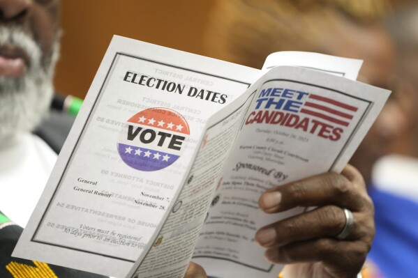 An attendee to a candidates forum reviews the event program that list those people seeking a statewide office in the November 7 election, in addition to a reminder of the general election and the general runoff of Nov. 28, in Vicksburg, Miss., on Oct. 26, 2023. (AP Photo/Rogelio V. Solis)