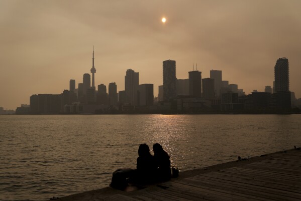 People watch the sunset as the smoke from wildfires drifts into Toronto on Wednesday, June 28, 2023. (Chris Young/The Canadian Press via AP)