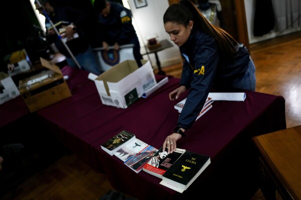 Federal agents put seized books inside boxes after displaying them to the press at Federal Police headquarters in Buenos Aires, Argentina, Wednesday, Sept. 13, 2023. Law enforcement officers say the books were printed by what they describe as the biggest manufacturer of Nazi propaganda in Argentina after carrying out raids this week, following a two year investigation to shut down the illegal printing press and arrest its operator. (AP Photo/Natacha Pisarenko)