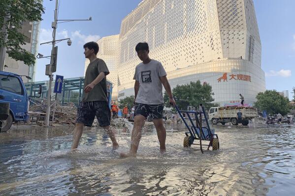 Residents walk along a flooded road in the aftermath of the heaviest recorded rainfall in Zhengzhou in central China's Henan province on Saturday, July 24, 2021. Rescuers used bulldozers and rubber boats to move residents out of flooded neighborhoods in central China on Saturday after torrential rains killed at least 56 people. (AP Photo/Dake Kang)