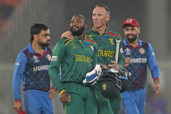 South Africa's Andile Phehlukwayo, second left, leaves the ground with teammate Rassi Van Der Dussen after South Africa won the ICC Men's Cricket World Cup match against Afghanistan in Ahmedabad, India, Friday, Nov. 10, 2023. (AP Photo/Ajit Solanki)
