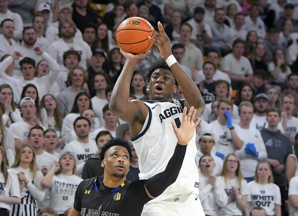 El delantero del estado de Utah, Great Osobor, dispara el balón mientras el guardia del estado de San José, Myron Amey Jr., defiende durante la primera mitad de un partido de baloncesto universitario de la NCAA el martes 30 de enero de 2024 en Logan, Utah.  (Eli Lucero/Herald Journal vía AP)