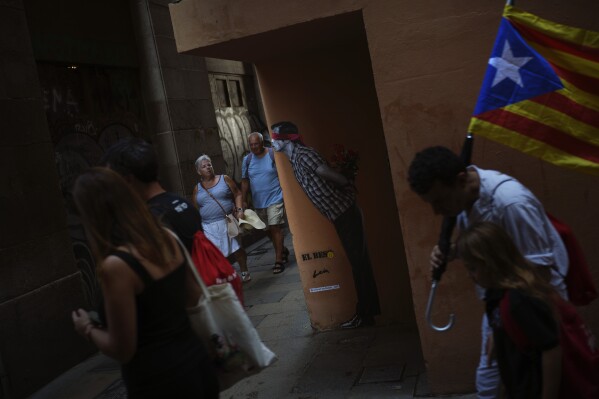 People, one of them carrying an esterada or independence flag, walk in downtown Barcelona, Spain, during the Catalan National Day on Sept. 11, 2023. (AP Photo/Emilio Morenatti)
