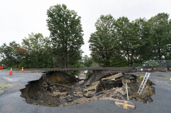 Train tracks on the Fitchburg Line extend over an area washed out by recent flooding, Wednesday, Sept. 13, 2023, in Leominster, Mass. The damage forced the closure of a commuter train line. (AP Photo/Robert F. Bukaty)