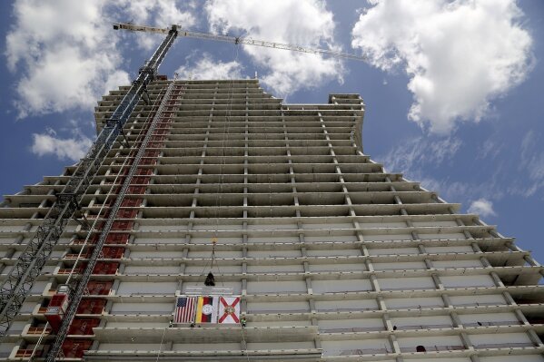 FILE - In this July 9, 2018 file photo, two of the final steel beams with signatures along with the American, Seminole Tribe, and the State flags are hoisted during the "Topping Out" ceremony where the beams of the highly anticipated project were ceremonially set atop the giant framework of the guitar shaped tower in Hollywood, Fla. It looks like the guitar Led Zeppelin's Jimmy Page played. But this one is 450 feet (137 meters) tall and is a light-beam hotel that the Seminole Tribe wants to become South Florida's latest tourist destination. The Guitar Hotel's grand opening is Thursday, Oct. 24, 2019, on the tribe's land in Hollywood. It's the latest step in the Seminole Hard Rock empire, which includes naming rights on the Miami-area stadium where the 2020 Super Bowl will be played. (Carl Juste/Miami Herald via AP, File)