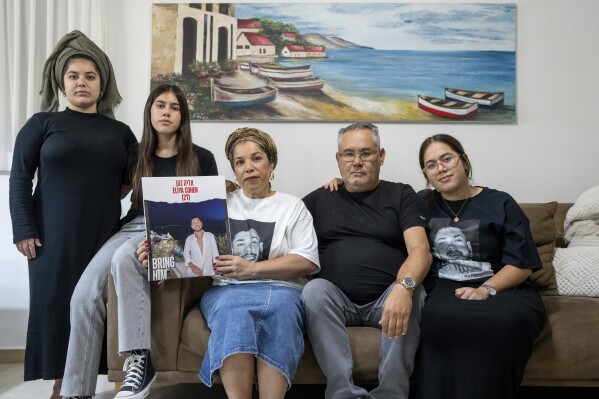 CORRECTS CONTEXT - Sigi and Momi Cohen, flanked on the couch by their children Yuval, Michal, and Tamar, hold up a portrait of their 27-year-old son, Eliya Cohen, in the family house in the village of Tzur Hadassah, Israel, Monday, Oct. 30, 2023. Cohen, an Israeli citizen, was abducted by Hamas militants from the 