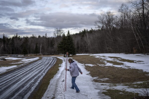 Kathy Miller removes snow plow markers from her driveway Monday, March 4, 2024, in Elmore, Vt. Miller describes herself as a Republican who hasn't drunk the Kool-Aid. She notes both Vermont and Elmore have shifted more Democratic over the years. But at Town Meeting, she says, political differences don't mean a thing."There's no animosity," she says. "People can talk about things. You shake hands with your neighbor when you leave." (AP Photo/David Goldman)