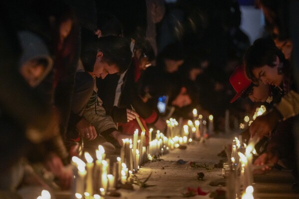 People light candles with the names of the detainees who were disappeared and executed during the military dictatorship led by Gen. Augusto Pinochet, at the National Stadium, which served as a detention center in the early years of the regime, during the event marking the 50th anniversary of the 1973 military coup that toppled the government of late President Salvador Allende, in Santiago, Chile, Monday, Sept. 11, 2023. (AP Photo/Esteban Felix)