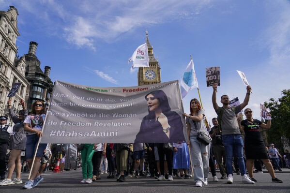 Demonstrators march in Parliament Square as they hold a banner, in London, Saturday, Sept. 16, 2023, as today marks the anniversary of the death of Mahsa Amini in Iran. (AP Photo/Alberto Pezzali)