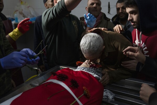 Ahmad Khdour, center right, takes part in the funeral preparations of his son Mohammad Khdour, 17, at the hospital's morgue in the West Bank city of Ramallah, Monday, Feb. 12, 2024. Khdour, a U.S. citizen born in Florida, was shot Saturday while driving with a cousin on a hillside by what his family alleges was Israeli fire. (AP Photo/Nasser Nasser)