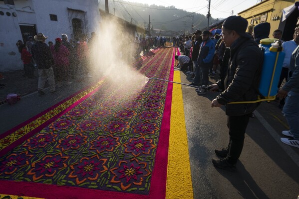 Members of the Alvarez family add the finishing touches to their sawdust carpet in preparation for a Holy Week procession, in Antigua, Guatemala, on Good Friday, March 29, 2024. (AP Photo/Moises Castillo)